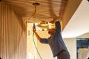 A man nailing decorative trim to the ceiling